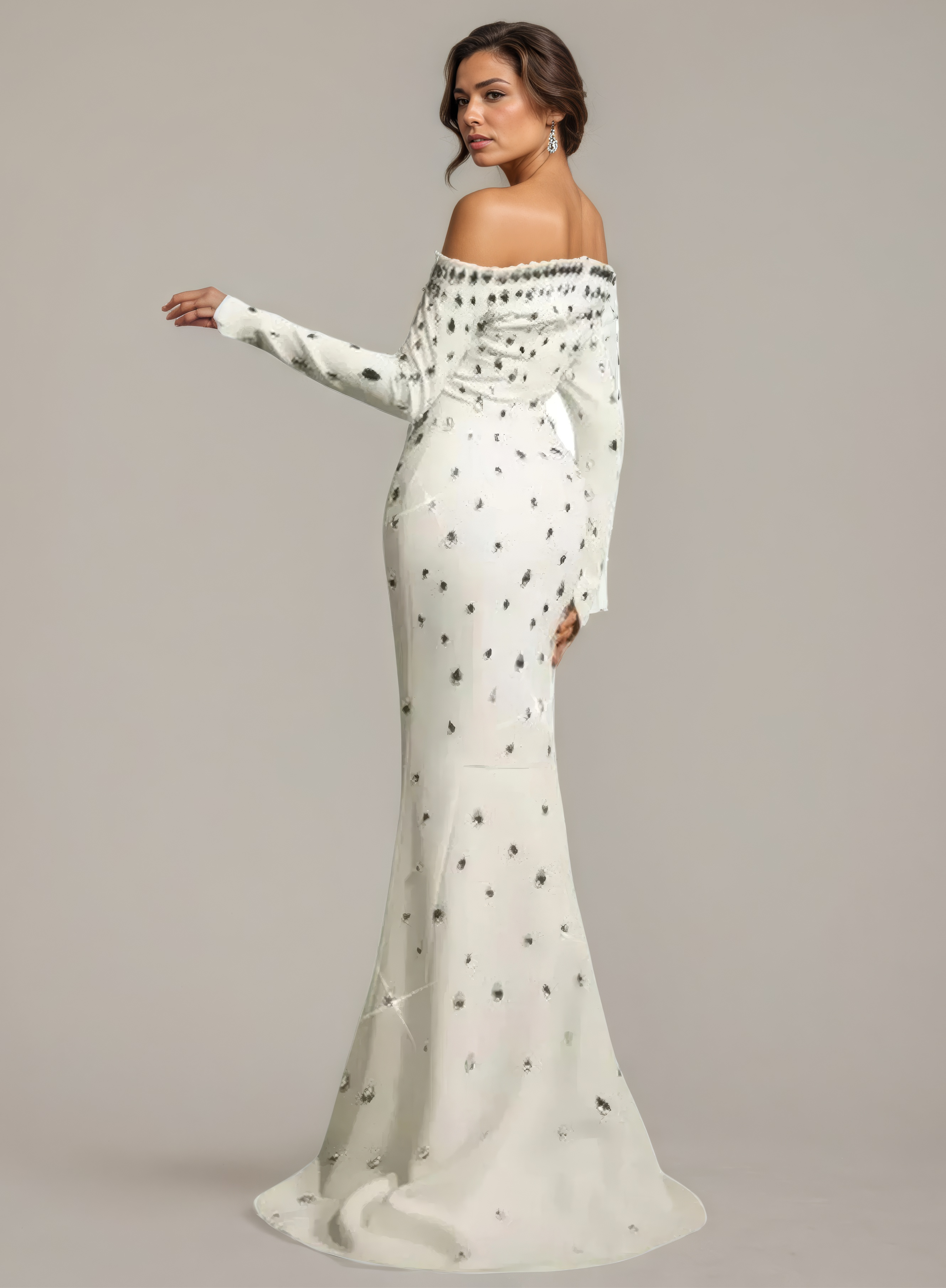 Woman wearing a white off-shoulder gown with black polka dots on a plain background