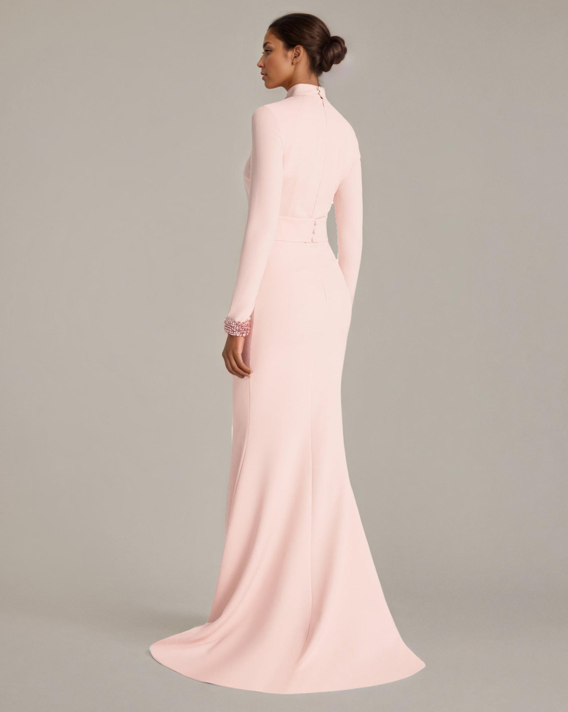 Woman wearing a long light pink dress against a neutral background